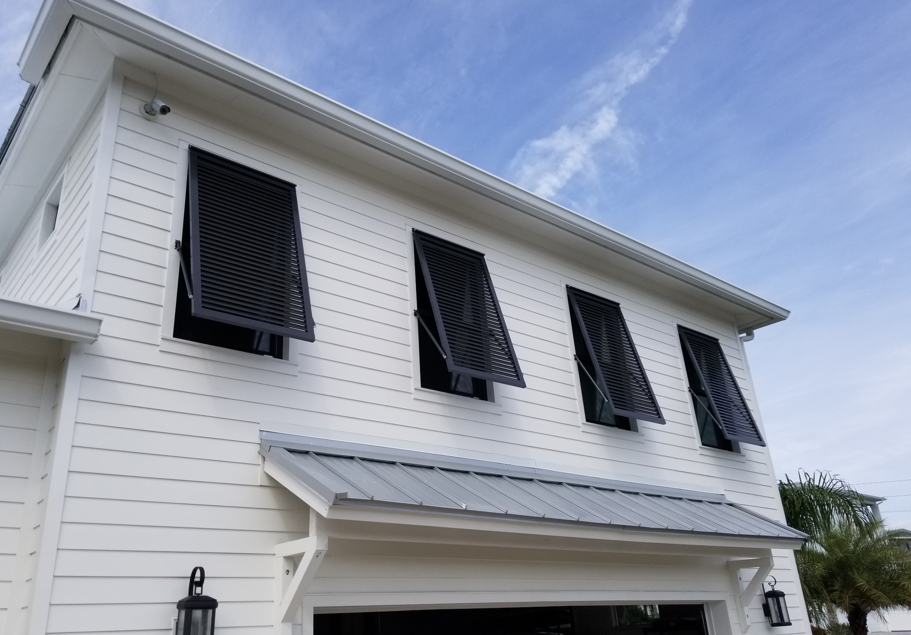 Bahama shutters installed over second-storey windows on a white Southwest Florida home